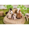 Three plush toy horses of varying sizes are arranged on a woven circular mat, with hay bales and greenery in the background. Produktbild-Vorschau
