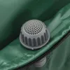 A close-up view of a gray valve with a perforated cap on a green tarp-like material, with a zipper visible. Náhľad obrázku produktu