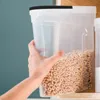 A hand is holding a clear plastic cereal container filled with cereal. Produktbild-Vorschau