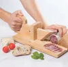 A person is using a wooden slicer to cut salami, with bread, cheese, tomatoes, and basil on the side. Produktbild-Vorschau