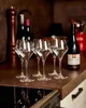 Six clear wine glasses are arranged on a brown countertop, with bottles and a pepper grinder in the background. Produktbild-Vorschau