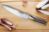 A Global G-2 chef's knife is placed on a wooden cutting board, with some radicchio and what appears to be ginger shavings scattered around. Anteprima dell’immagine prodotto