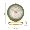 A green alarm clock with a gold stand is shown against a white background with measurement indicators. Produktbild-Vorschau