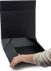 A hand is shown folding a black gift box. Podgląd zdjęcia produktu