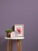 A small round table with decorative items on it, placed against a purple wall. Podgląd zdjęcia produktu