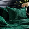 A close-up view of a bed with emerald green velvet bedding, featuring a quilted palm leaf pattern. A vase of light-colored flowers is visible in the background. Voir les images du produit
