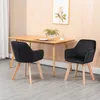Two black dining chairs with wooden legs are placed around a wooden dining table in a room with a light wood paneled wall and a framed picture of a flower. Náhled obrázku produktu
