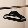 A set of black velvet hangers hanging on a closet rod. Anteprima dell’immagine prodotto