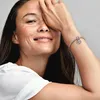 A woman's arm is shown with a bracelet and charm, while her face is partially obscured by her hand. Podgląd zdjęcia produktu