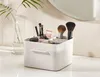 A makeup organizer on a white surface with a plant in a vase and a mirror in the background. Náhled obrázku produktu