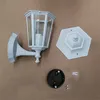 A white outdoor wall lamp and its mounting hardware are laid out on a brown surface. Produktbild-Vorschau