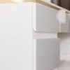 A close-up view of white drawers with a gold trim on a desk. Produktbild-Vorschau