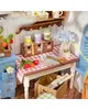 A miniature kitchen scene with various items on a table and shelf. Podgląd zdjęcia produktu