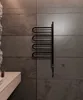 A black towel warmer mounted on a gray tiled wall in a bathroom. Náhľad obrázku produktu
