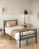 A bedroom setting with a single black metal bed frame. Náhled obrázku produktu