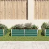 Three green raised garden beds filled with soil and plants are arranged on a lawn in front of a wooden fence and a textured wall. Podgląd zdjęcia produktu