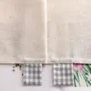 A close-up view of the bottom edge of two fabric panels, showing decorative tabs with a gingham pattern. Produktbild-Vorschau