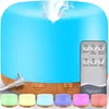 A blue aroma diffuser with a wood-grain base, emitting a plume of steam. A remote control and several colored lights are displayed in front of it. Anteprima dell’immagine prodotto