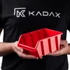 A person wearing a black t-shirt with a logo is holding a red plastic storage bin. Náhled obrázku produktu