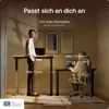 Two people are using standing desks in a modern office setting. Produktbild-Vorschau