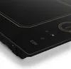 A close-up view of a black induction cooktop with gold accents and touch controls. Podgląd zdjęcia produktu