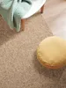 A close-up view of a rug with a round cushion and a folded blanket on a chair. Anteprima dell’immagine prodotto