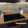 A modern kitchen countertop with a black induction stovetop and a concrete backsplash. Produktbild-Vorschau