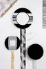 A flat lay of black and white patterned plates arranged on a white background with decorative elements. Produktbild-Vorschau
