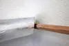 A close-up view of a copper pipe inserted into a piece of silver-colored insulation material, set against a textured white wall. Produktbild-Vorschau