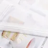 A close-up view of a white sheer curtain with a decorative satin band, showing a slice of cake underneath. Produktbild-Vorschau