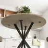 Underside view of a round dining table with a floral arrangement on top, set in a kitchen environment. Produktbild-Vorschau