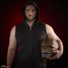 A man wearing a black hooded vest holds a damaged helmet in front of a red and black gradient background. Náhled obrázku produktu