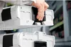 A hand is shown connecting two white storage boxes with black accents. Náhled obrázku produktu