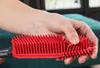 A hand holding a red silicone brush. Podgląd zdjęcia produktu
