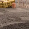 A close-up view of a fluffy gray rug with a yellow cushion and a pink candle in the background. Voir les images du produit