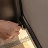 A hand is shown operating a latch on a dark-colored screen or panel, possibly part of a pergola or outdoor structure. Produktbild-Vorschau