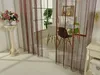 A room with string curtains, a table and chairs, and a vase of flowers. Produktbild-Vorschau