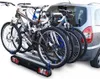A rear-mounted bicycle rack with four bicycles attached to the back of a silver vehicle. Produktbild-Vorschau