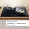 A Bosch induction cooktop with an integrated downdraft ventilation system is shown in use, with a pot of vegetables and a frying pan with fish cooking on it. Steam is rising from both. Produktbild-Vorschau