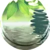 A stack of smooth, dark stones sits on rippling water, with green leaves in the background. Náhled obrázku produktu