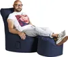 A bald man with glasses and a beard sits relaxed in a navy blue beanbag chair with an ottoman, wearing a white t-shirt with a woman's face printed on it and earbuds. Produktbild-Vorschau