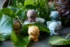 Several small, stylized animal figurines are arranged among lush green plants. Produktbild-Vorschau