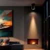 A modern living room with a fireplace, artwork, and a sofa, illuminated by a ceiling light. Náhled obrázku produktu