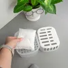 A person's hand is holding a white desiccant packet over a white plastic dehumidifier container, with a white pot holding a green plant in the background. Voir les images du produit