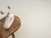 A white vase with two decorative spheres on sticks sits on a wooden table. Produktbild-Vorschau