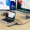 A laptop and two external monitors are set up on a wooden desk, connected by a docking station. Produktbild-Vorschau
