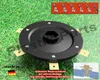 A close-up view of a black trimmer head with gold blades, set against a backdrop of green grass. Several small screws are also visible. Produktbild-Vorschau