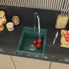 A kitchen sink with running water and tomatoes, surrounded by jars of food and kitchen utensils. Anteprima dell’immagine prodotto