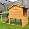A wooden chicken coop with a green roof sits on a grassy lawn in front of a wooden fence and a house. Produktbild-Vorschau
