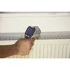 A hand holding an infrared thermometer pointed at a radiator. Produktbild-Vorschau